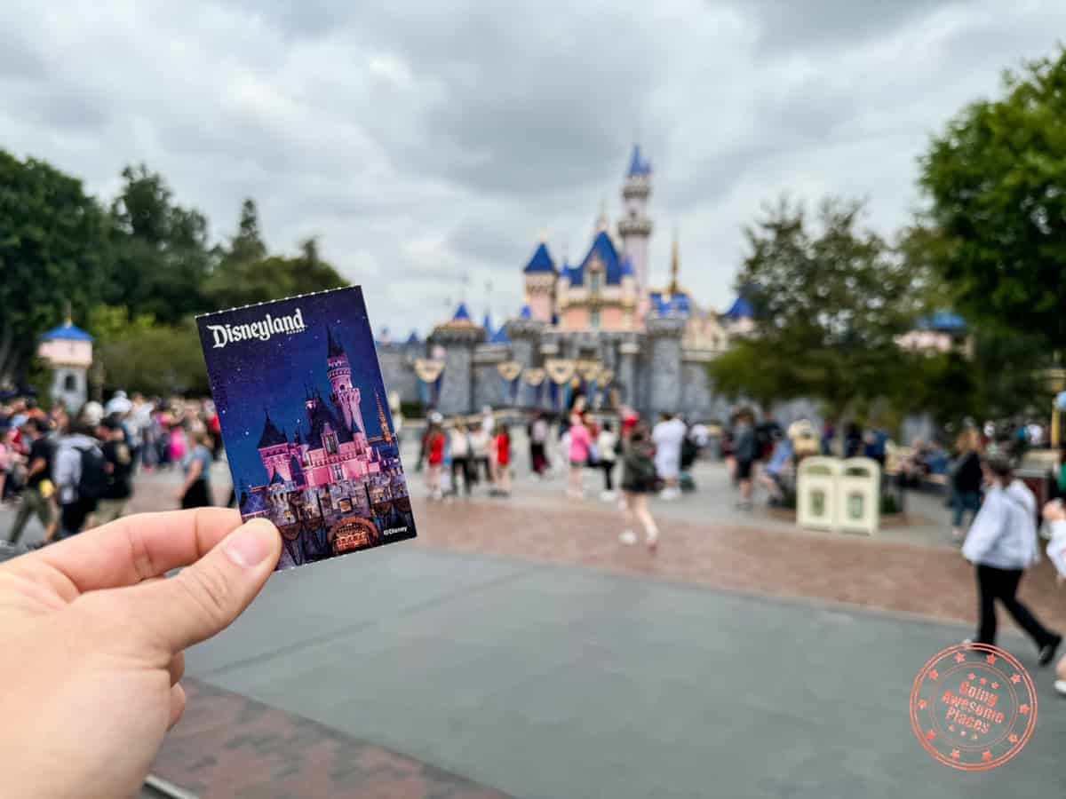 disneyland ticket held in front of the castle