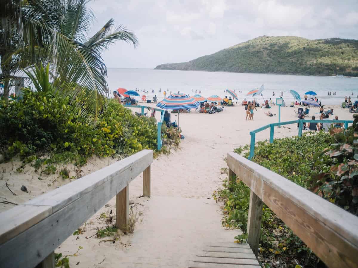 walking down to flamenco beach with people sitting under umbrellas 