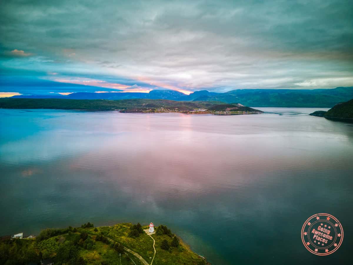 aerial shot with woody point lighthouse below and gros morne mountain behind