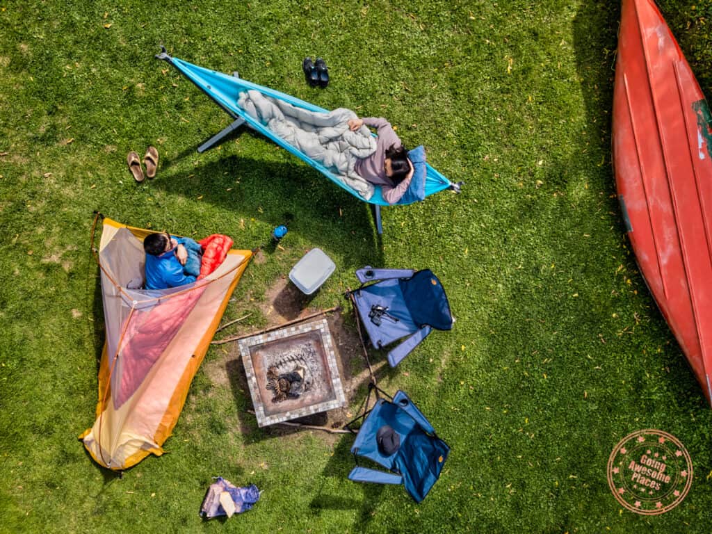 hammock swiftlet around the campsite with tent, firepit, chairs, and canoe
