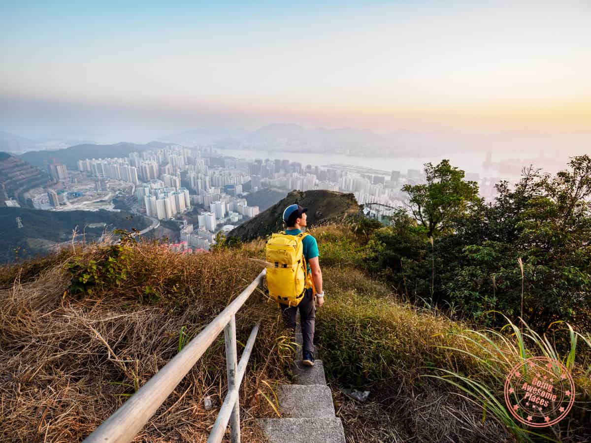 man with yellow backpacking hiking down the stairs of kowloon peak at sunset