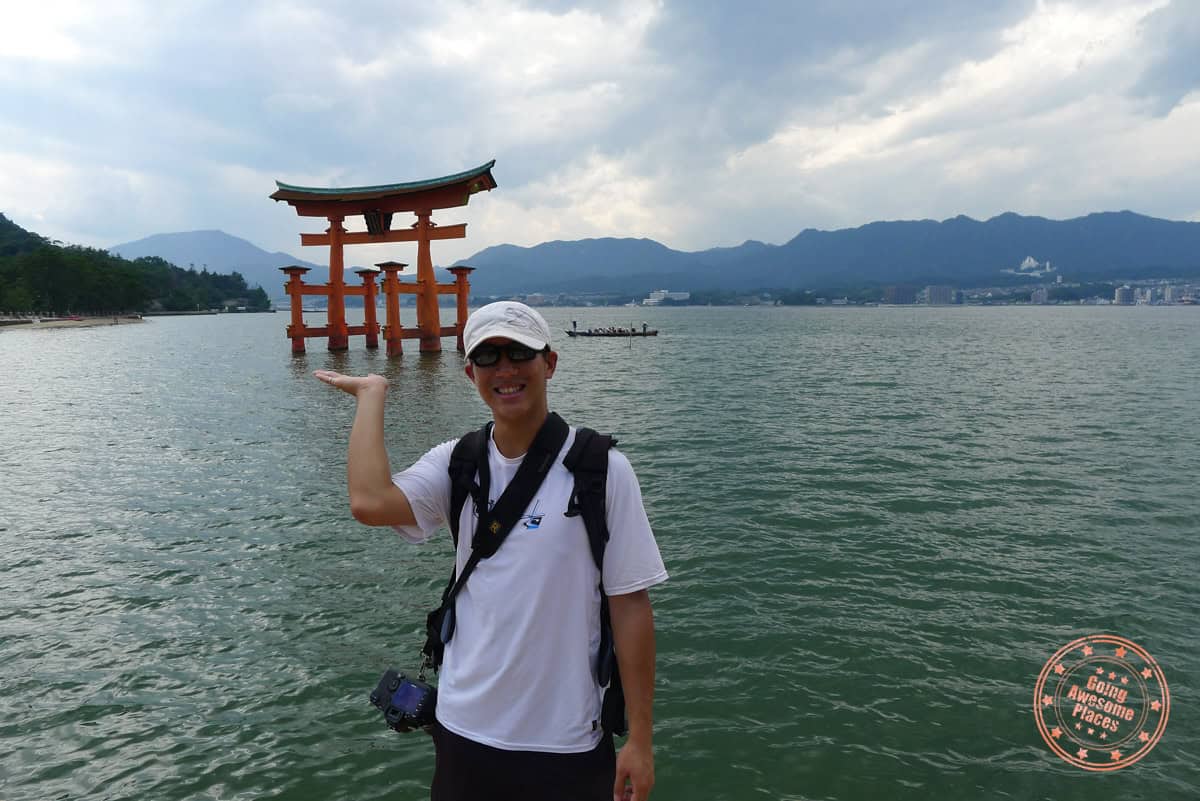 standing in front of a floating torii gate in hiroshima