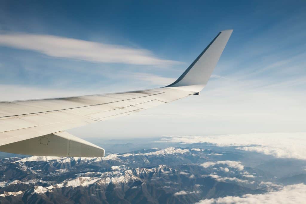 airline plane wing flying over mountains