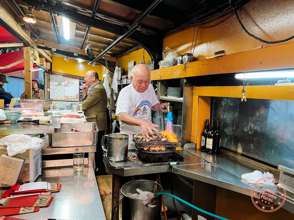 izakaya toyo in osaka running his hands through the tuna cheeks with the flamethrower on