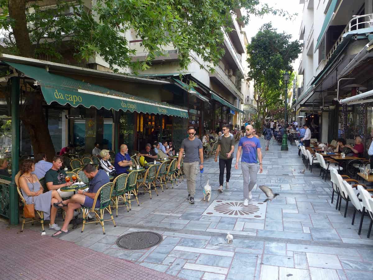 pedestrians outside restaurants on a cobblestone street in kolonaki