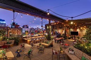 moxy nyc east village outdoor bar and lounge under night sky and string lights