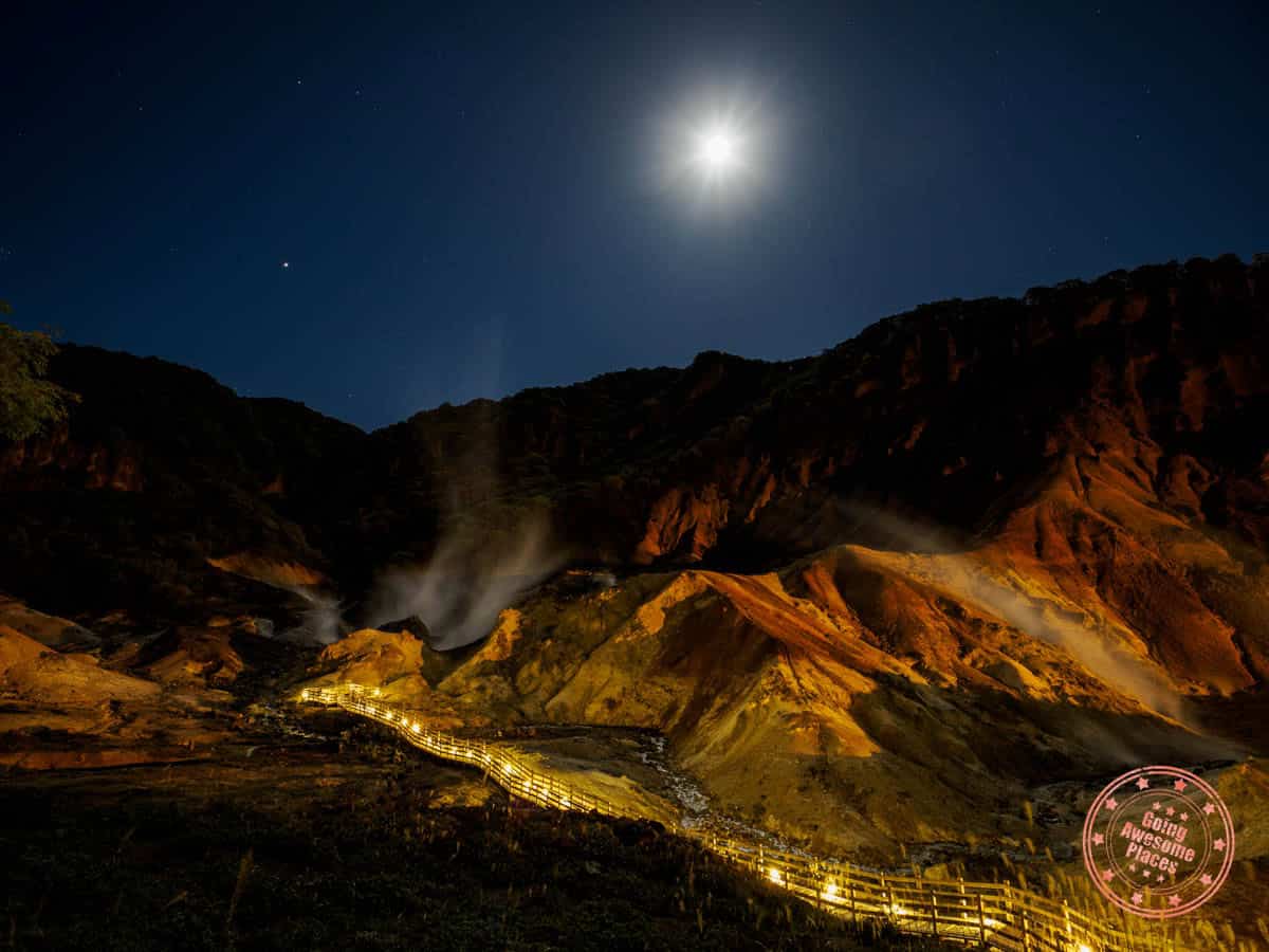 wooden walkway lit up at night leading to jigokudani