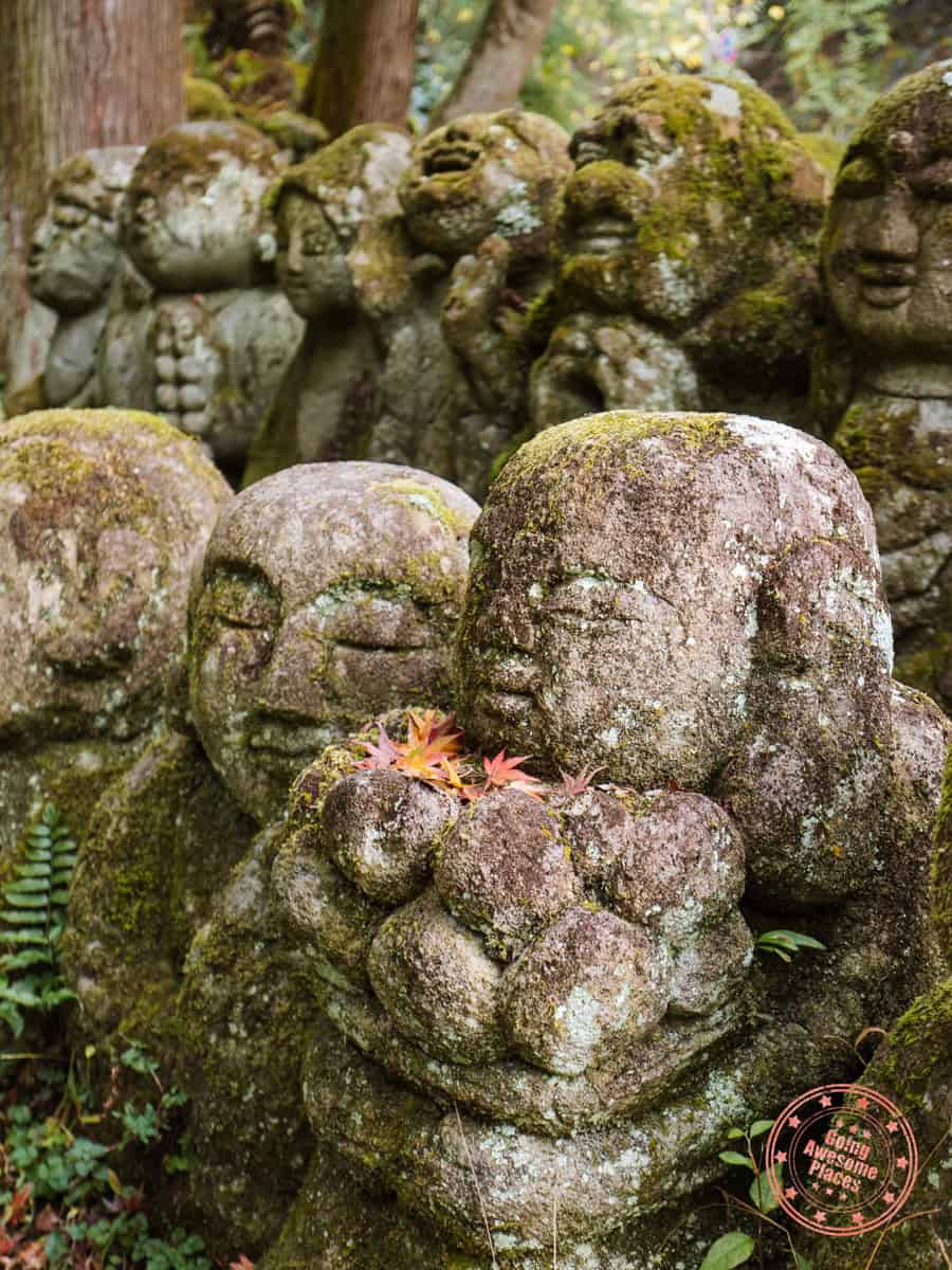 whimsical statue of otagi nenbutsuji temple holding small autumn leaves