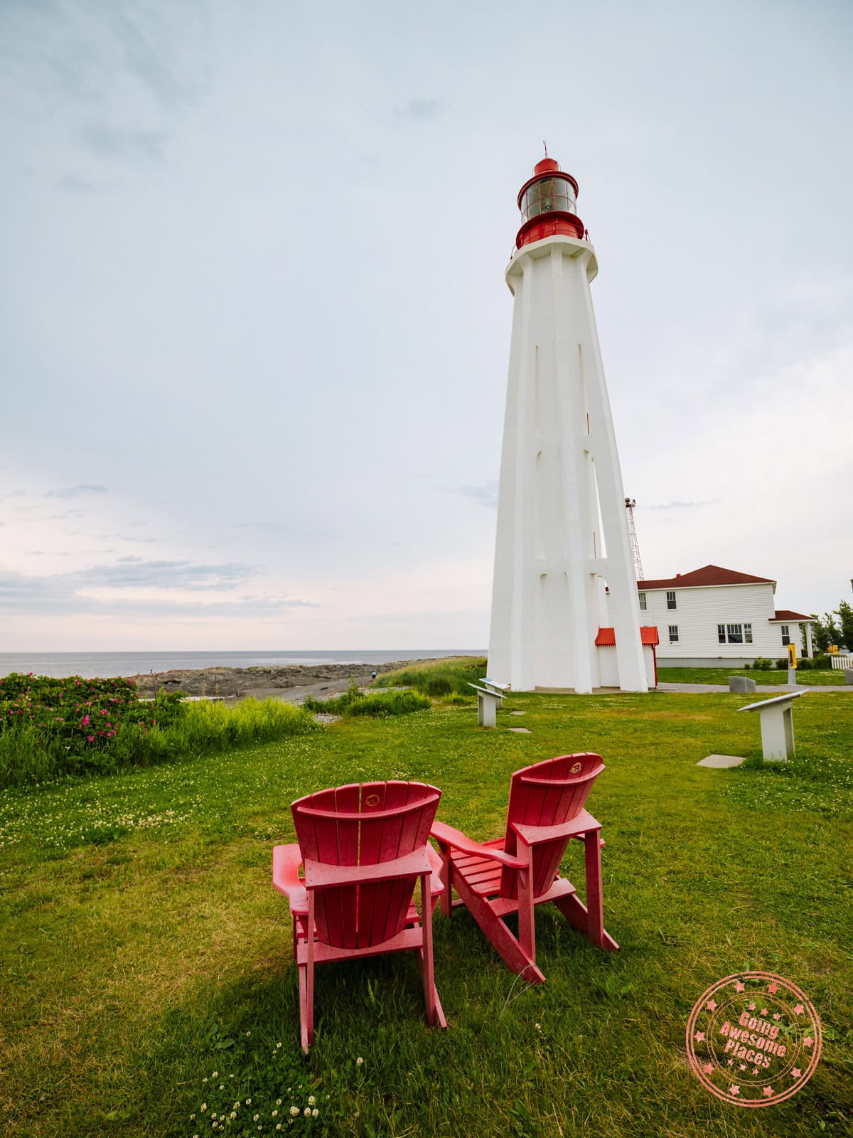 pointe-au-pere lighthouse with parks canada red chairs in the foreground