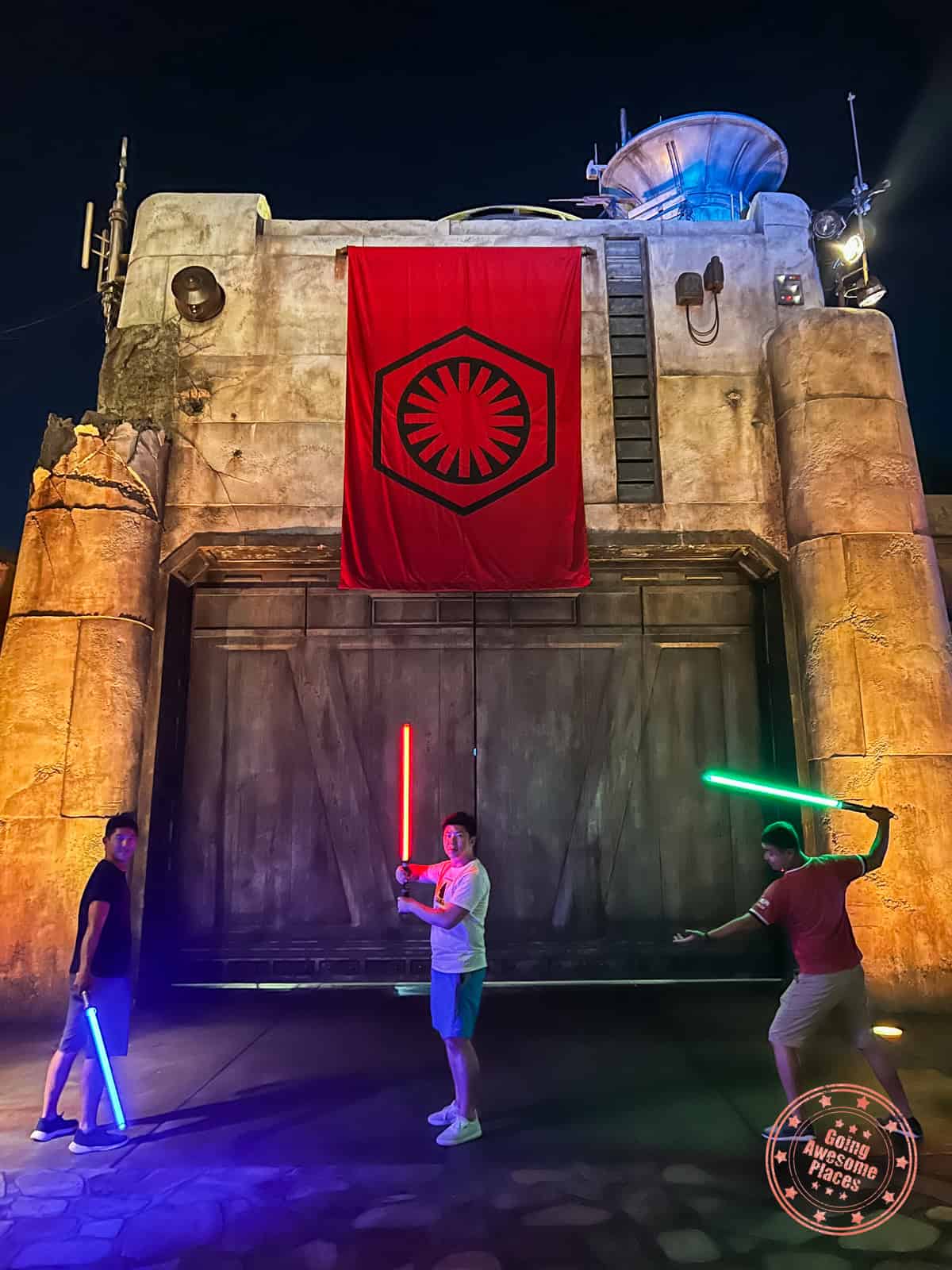 3 star wars fans wielding lightsabers in galaxy's edge at disneyland