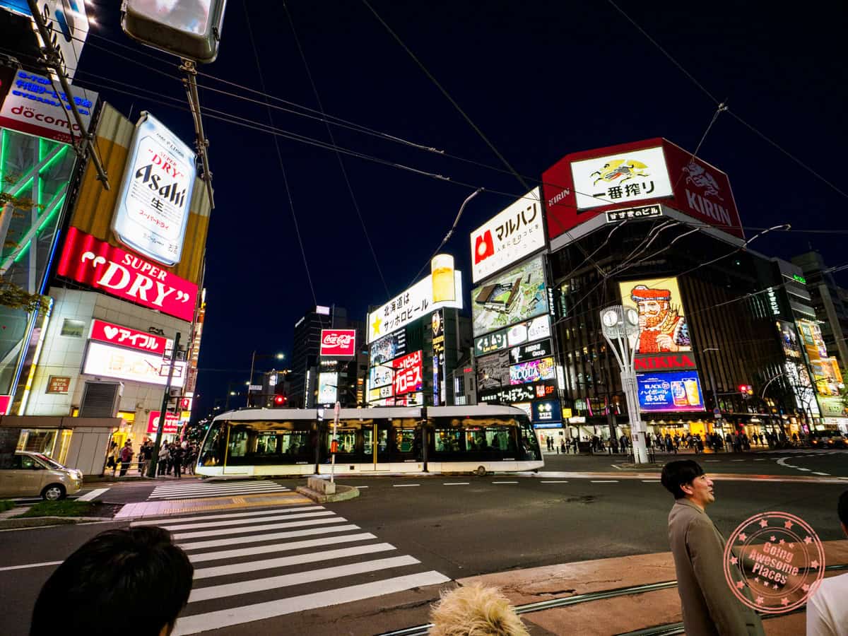 busy intersection in susukino lit up at night with different signs
