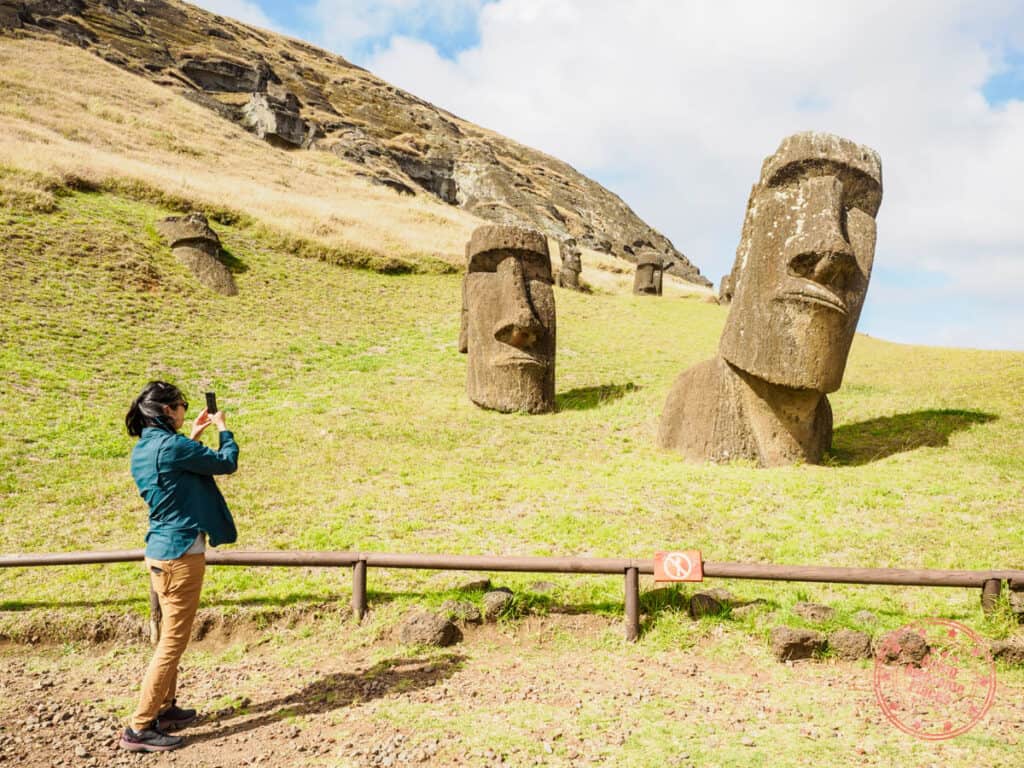 woman taking photo of moai at rano raraku when visiting easter island