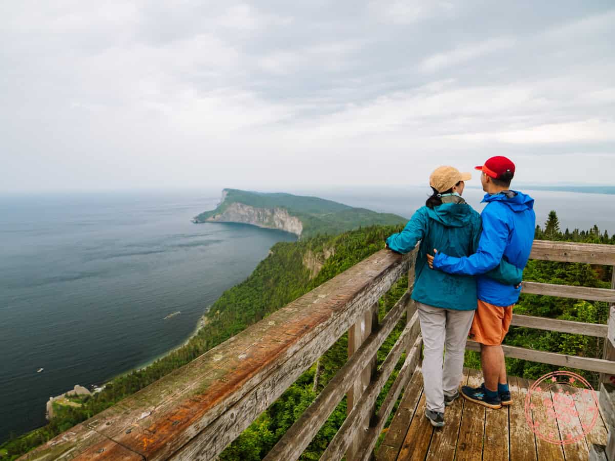 couple standing on wooden observation tower looking out into forillon national park at mont saint alban