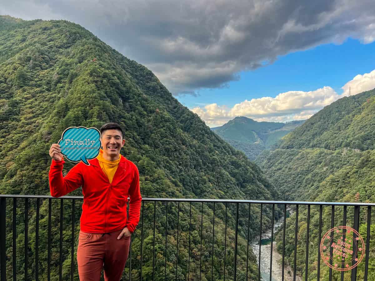 will holding an iyaonsen sign with iya valley in the background